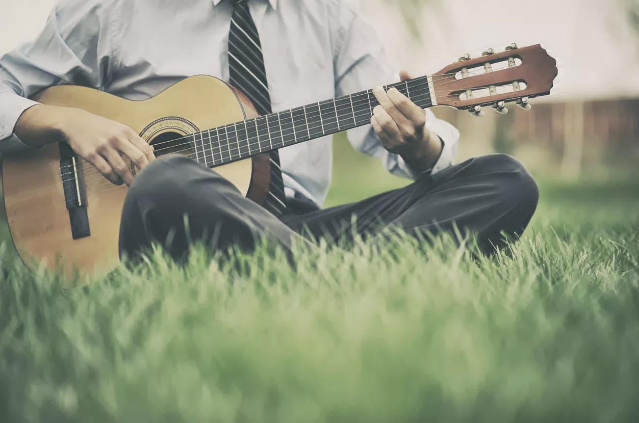 Businessman playing guitar in a field